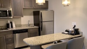 Una cocina moderna con encimeras de granito, electrodomésticos de acero inoxidable y una isla central con asientos.