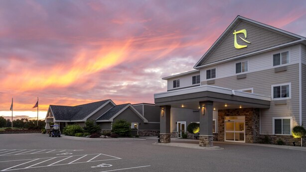 Un hotel de diseño moderno, con una entrada destacada de fachada de piedra y un gran letrero iluminado.