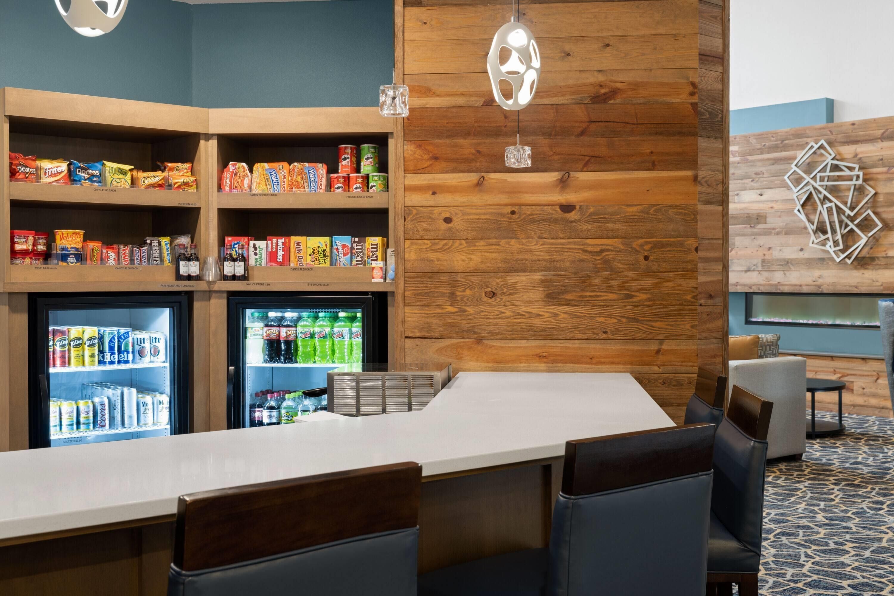 A bar area with seating, a snack shelf, and a refrigerator stocked with beverages.