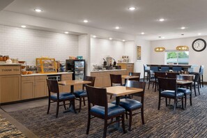 Un hall de hotel con mostrador de recepción, zona de estar y cocina al fondo.