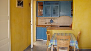 Una cocina con armarios azules, una mesa de comedor con mantel escocés y sillas.