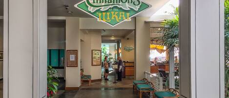 A hotel lobby with a sign reading "Cinnamon's at the Ilkaki". There are wooden chairs and a reception desk in the center.