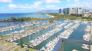 A marina filled with numerous boats, a city skyline in the background, and a clear blue sky. - Ilikai by Luana Hawaii Vacation Rentals (Honolulu)