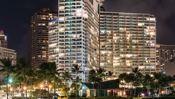 A high-rise hotel with multiple floors, large windows, and a well-lit facade. - Ilikai by Luana Hawaii Vacation Rentals (Honolulu)