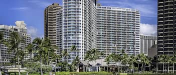 A beachfront hotel with multiple high-rise buildings, palm trees, and a sandy beach.