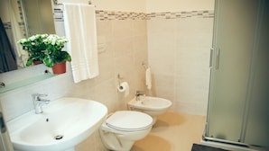 Un bany amb rentatge, vàter, bidet i zona de dutxa.