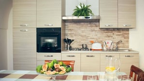 Una cuina moderna amb armaris de fusta, forn integrat, un rentaplat i un taulell amb una planta.