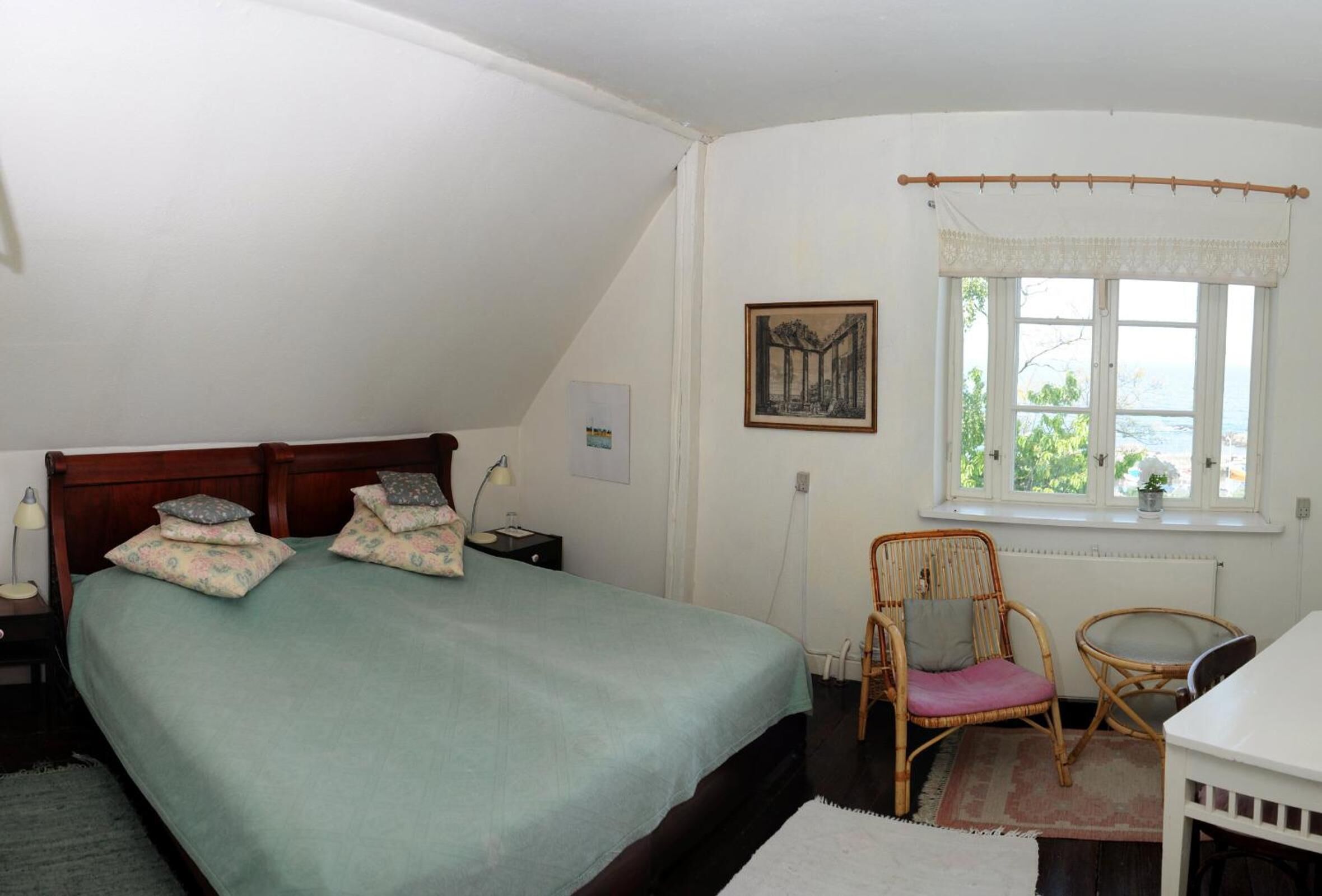 A bedroom with a bed, two bedside tables, a nightstand, a window with a view, and a chair.