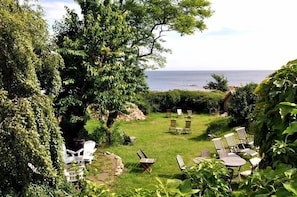 A garden with outdoor seating, a view of the sea, and lush greenery. - Danchelshus (Allinge)