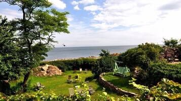Un jardin avec une balançoire, des chaises et une vue sur la mer.