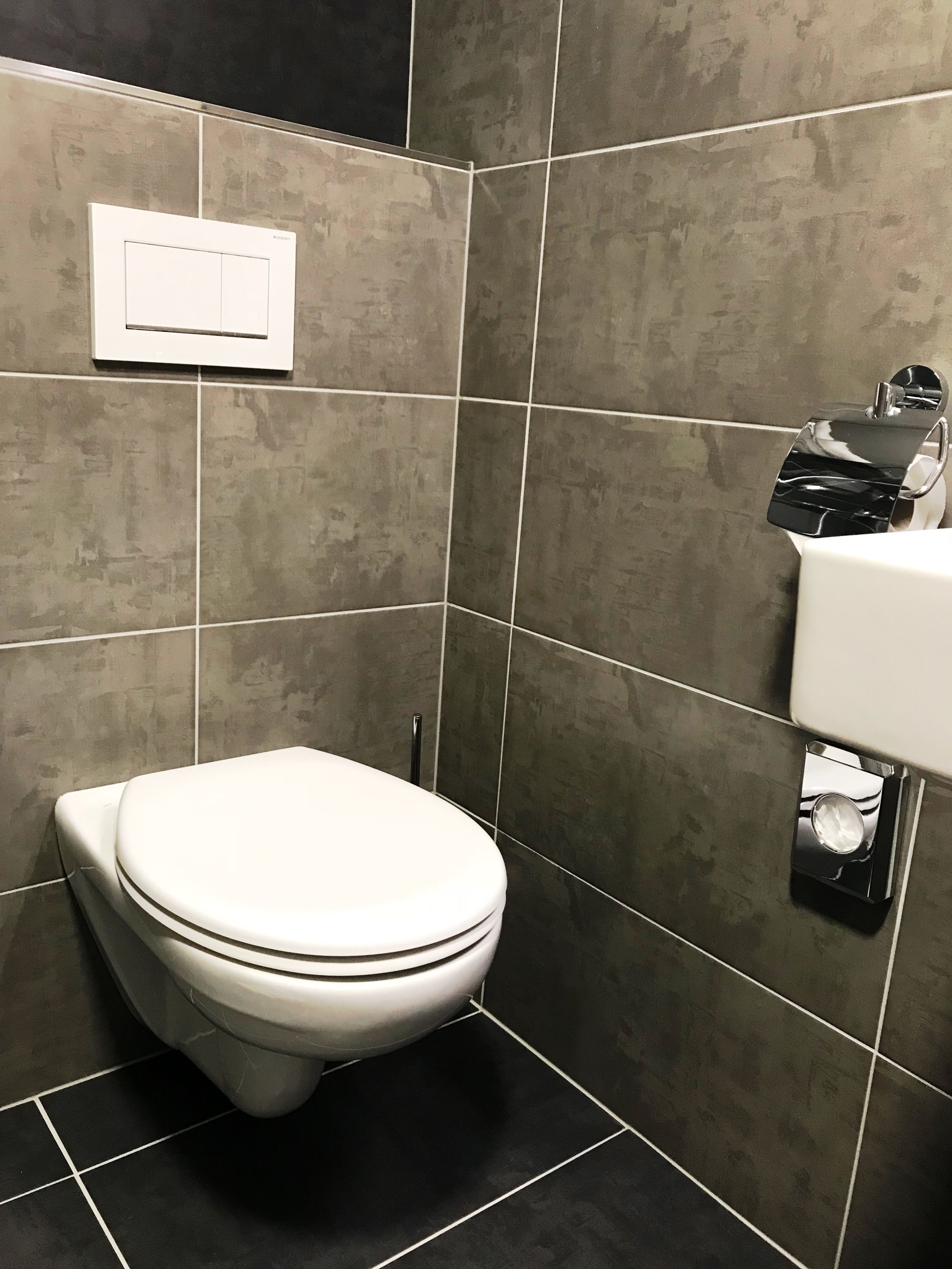 Un baño moderno con inodoro, lavamanos empotrado y dispensador de toallas.