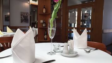 A dining table set with white napkins, a wine glass, and a knife.