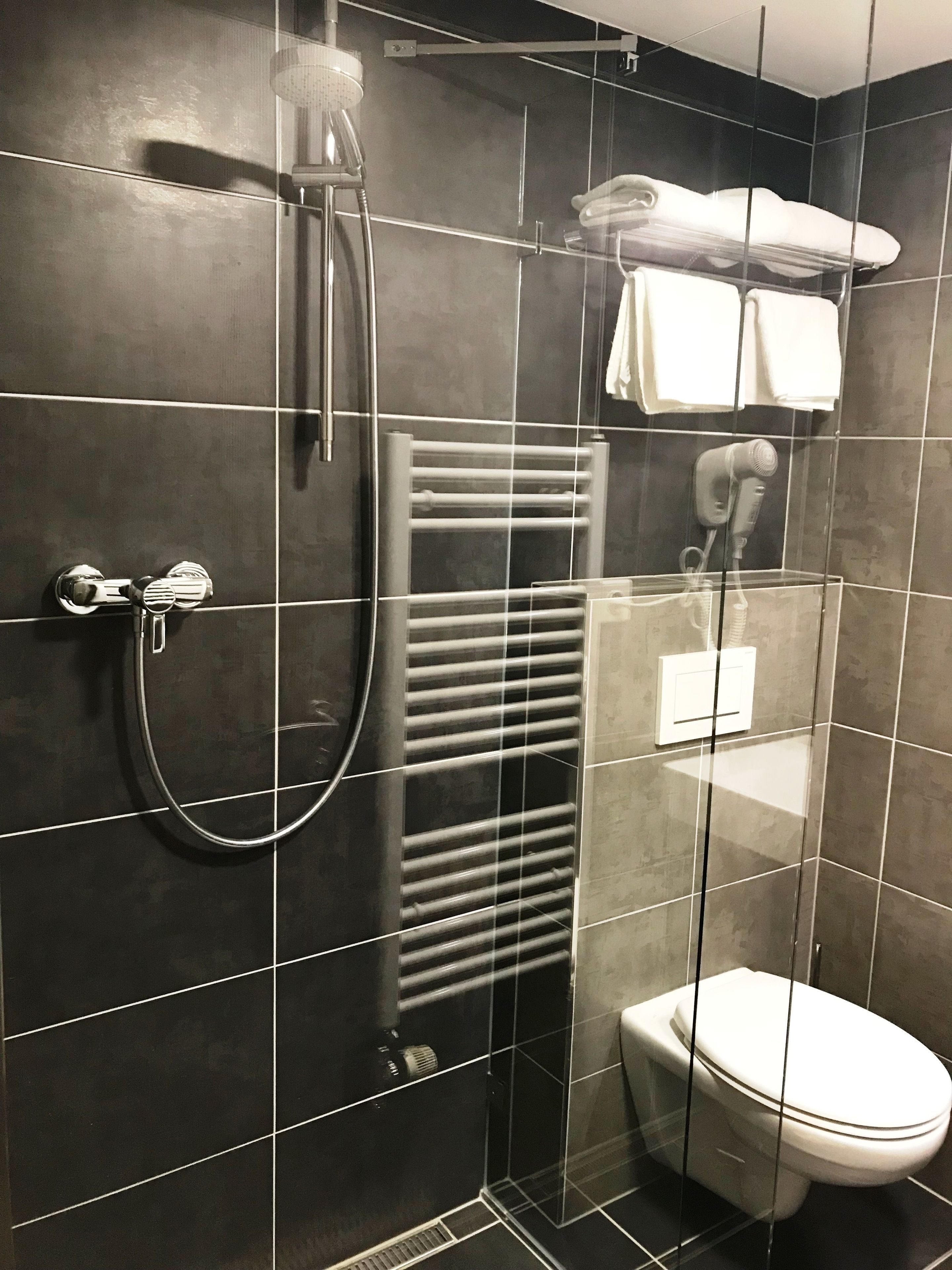 Et moderne badeværelse med brusekabine i glas, indbygget håndklædestang, hårtørrer og toilet.
