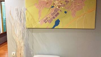 Una habitación con un mapa grande en la pared, un banco blanco y una escultura alta y estilizada.