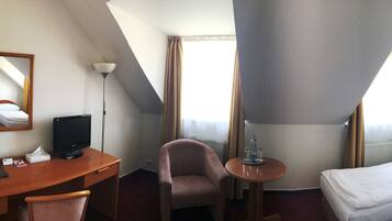 A hotel room with a bed, desk, chair, and a small table.