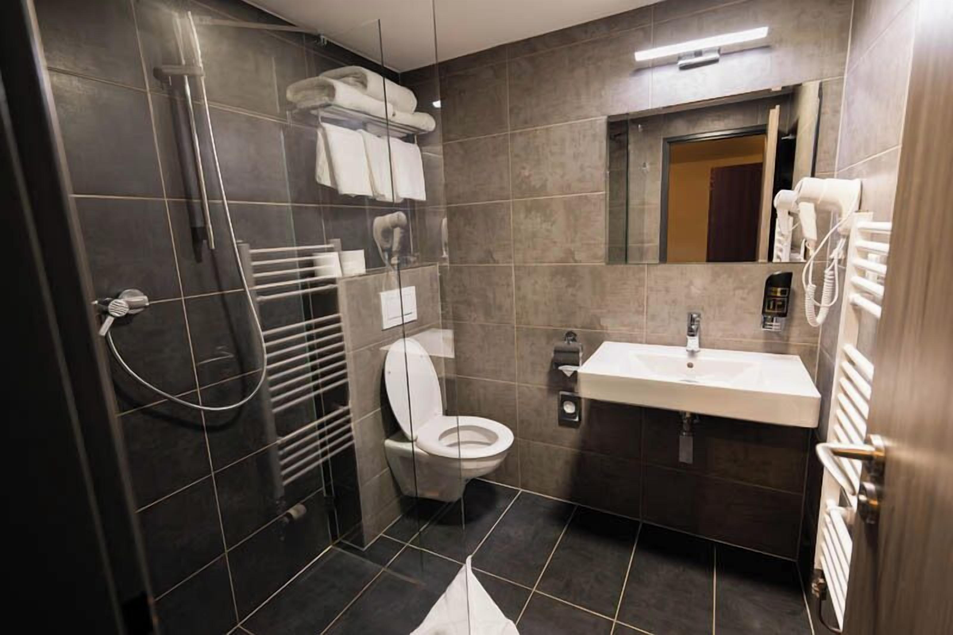 A modern bathroom with a shower, toilet, and sink.