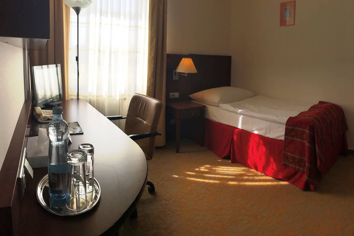 A hotel room with two beds, a desk with a computer, and a chair.