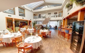 Enjoy meals in this stylish dining area with a high ceiling, round tables, and comfortable seating.