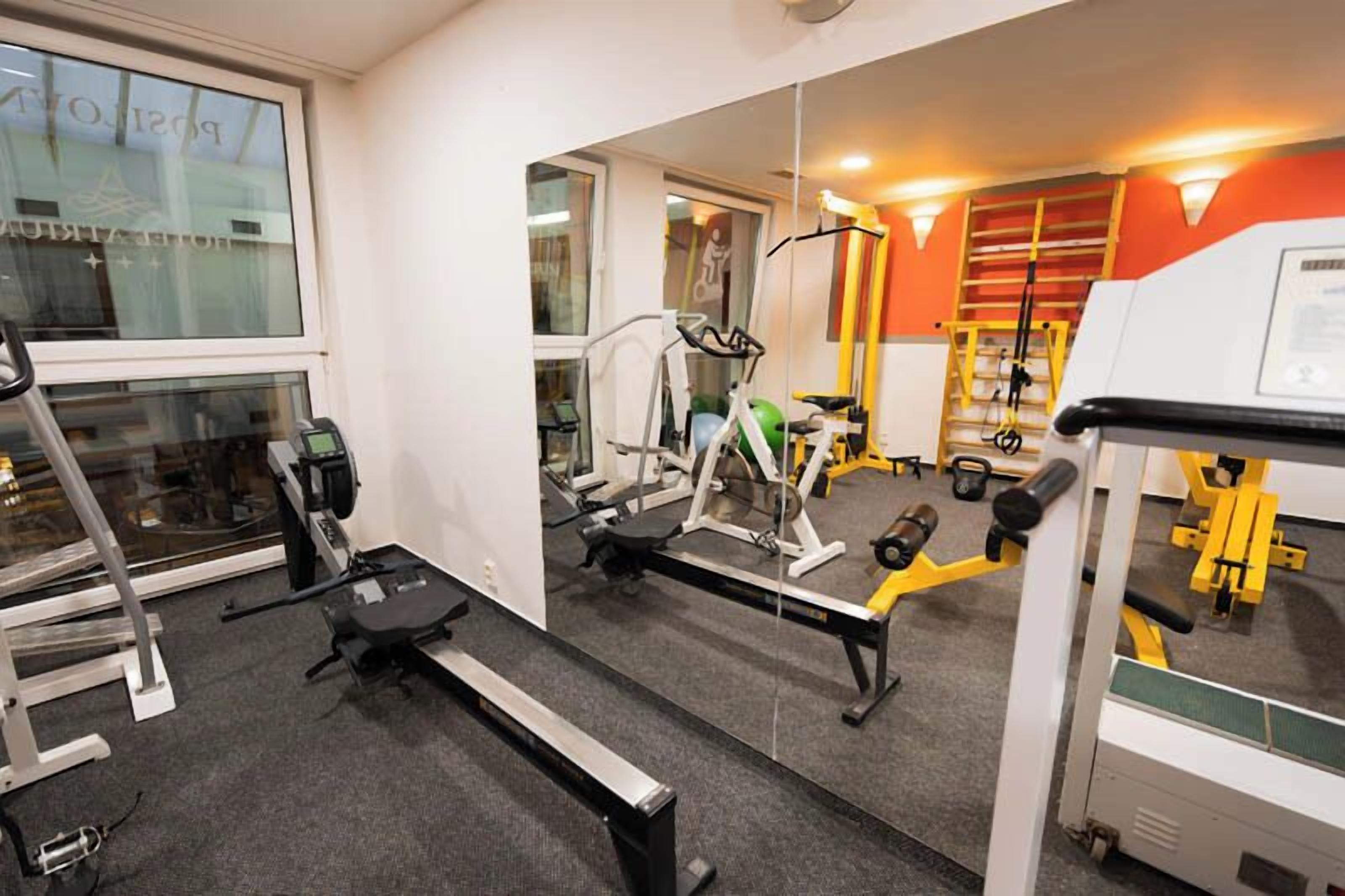A gym with various exercise equipment, a treadmill, and a mirror reflecting the room.