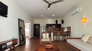 A spacious living area with a wooden coffee table, a sofa, and a kitchen in the background. - Tulum Nah (Tulum)