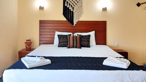 A neatly made bed with white linens, a dark blue throw blanket, and two white towels folded at the foot of the bed. - Tulum Nah (Tulum)