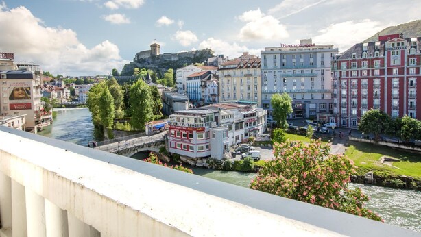Une vue sur la ville, avec ses bâtiments historiques, un fleuve et un château en arrière-plan, le tout surplombant les rives.