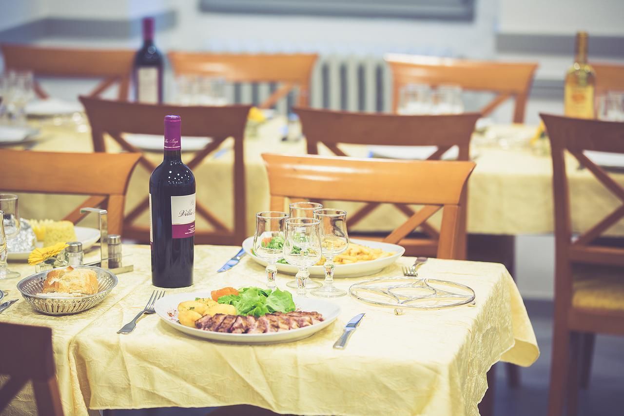 A dining table set with plates of food, wine glasses, and cutlery.