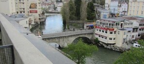 A river with a bridge, buildings, and a boat dock. - Hotel Notre- Dame de France (Lourdes)