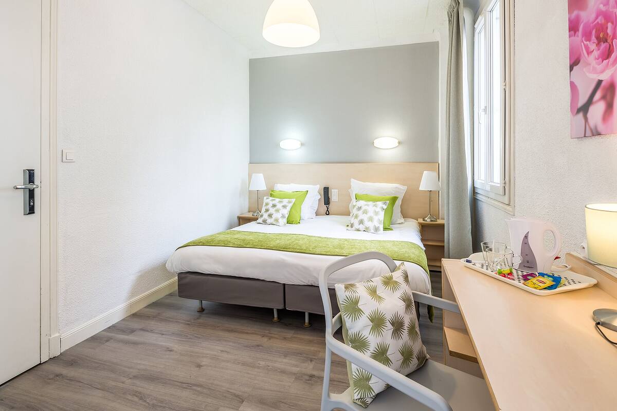Een hotelkamer met een bed, nachtkastjes, een bureau en een stoel.