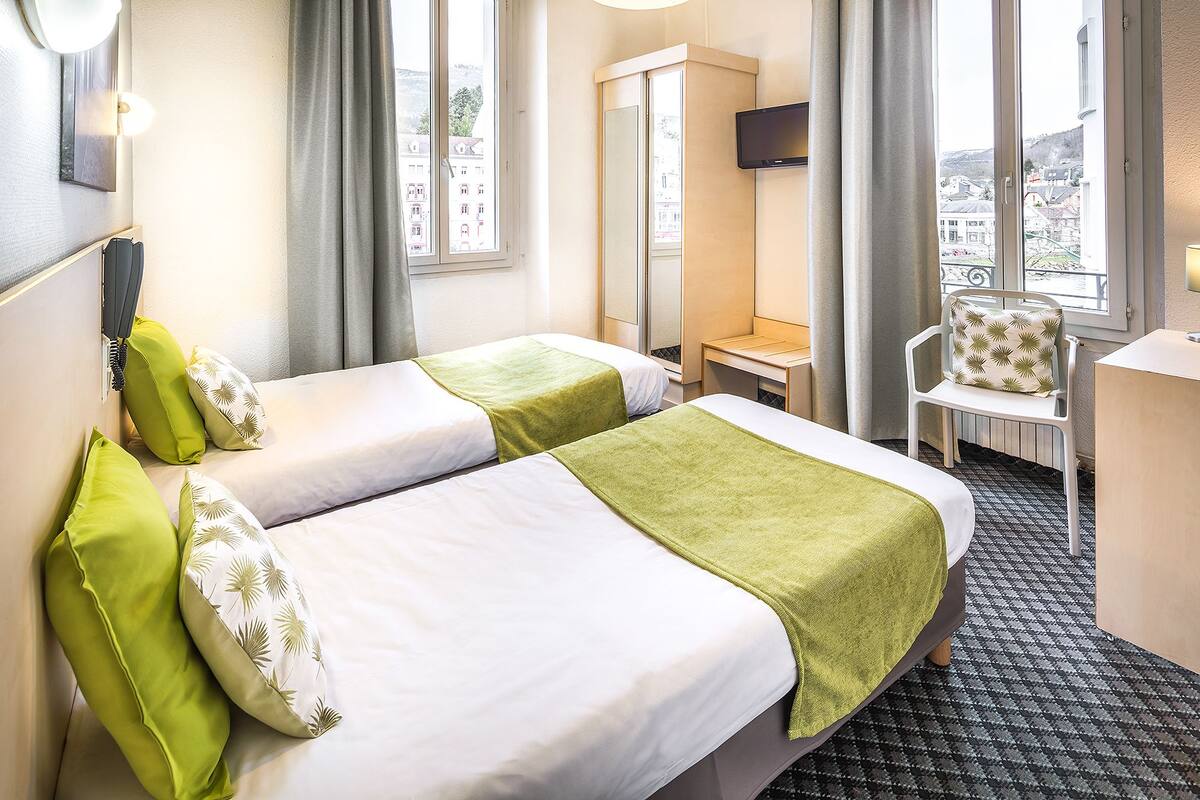 Een hotelkamer met twee bedden, een bureau, een stoel en een televisie.