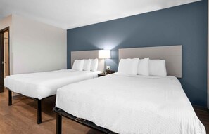 A hotel room with two beds, a nightstand with a lamp, and a door to the left. - Extended Stay America Select Suites - Charlotte - Northlake (Charlotte)