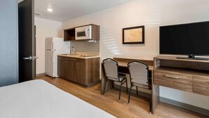 A compact hotel room with a kitchenette, a bed, a desk with two chairs, and a television. - Extended Stay America Suites - Charlotte - Matthews (Matthews)