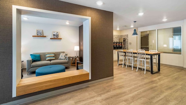 A modern living room with a sofa, ottoman, and a dining area with a table and chairs. - Extended Stay America Suites - Charlotte - Matthews (Matthews)