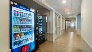 A hallway with vending machines and an exit sign. - Extended Stay America Suites - Charlotte - Matthews (Matthews)
