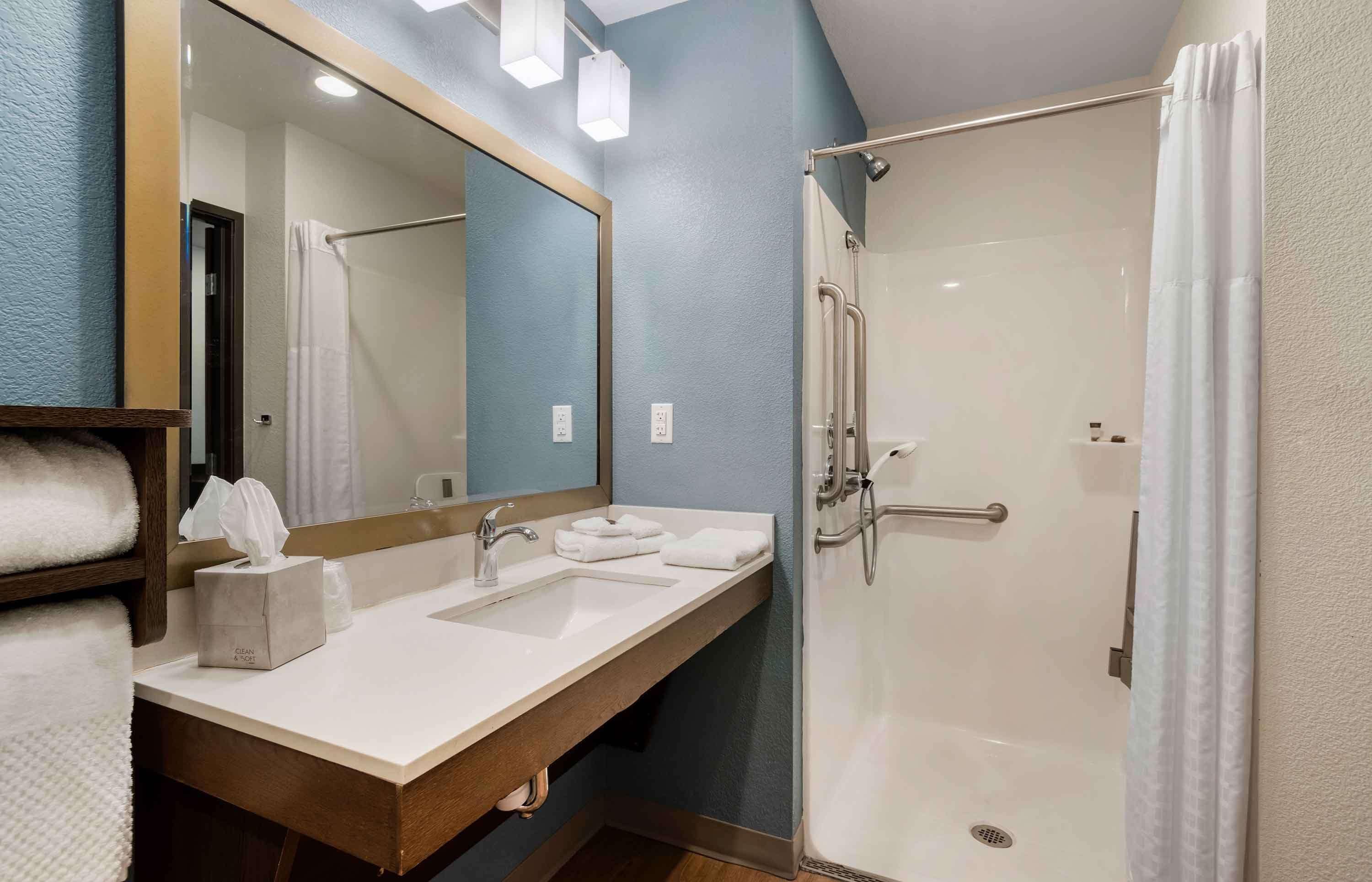 A bathroom with a sink, mirror, and shower.