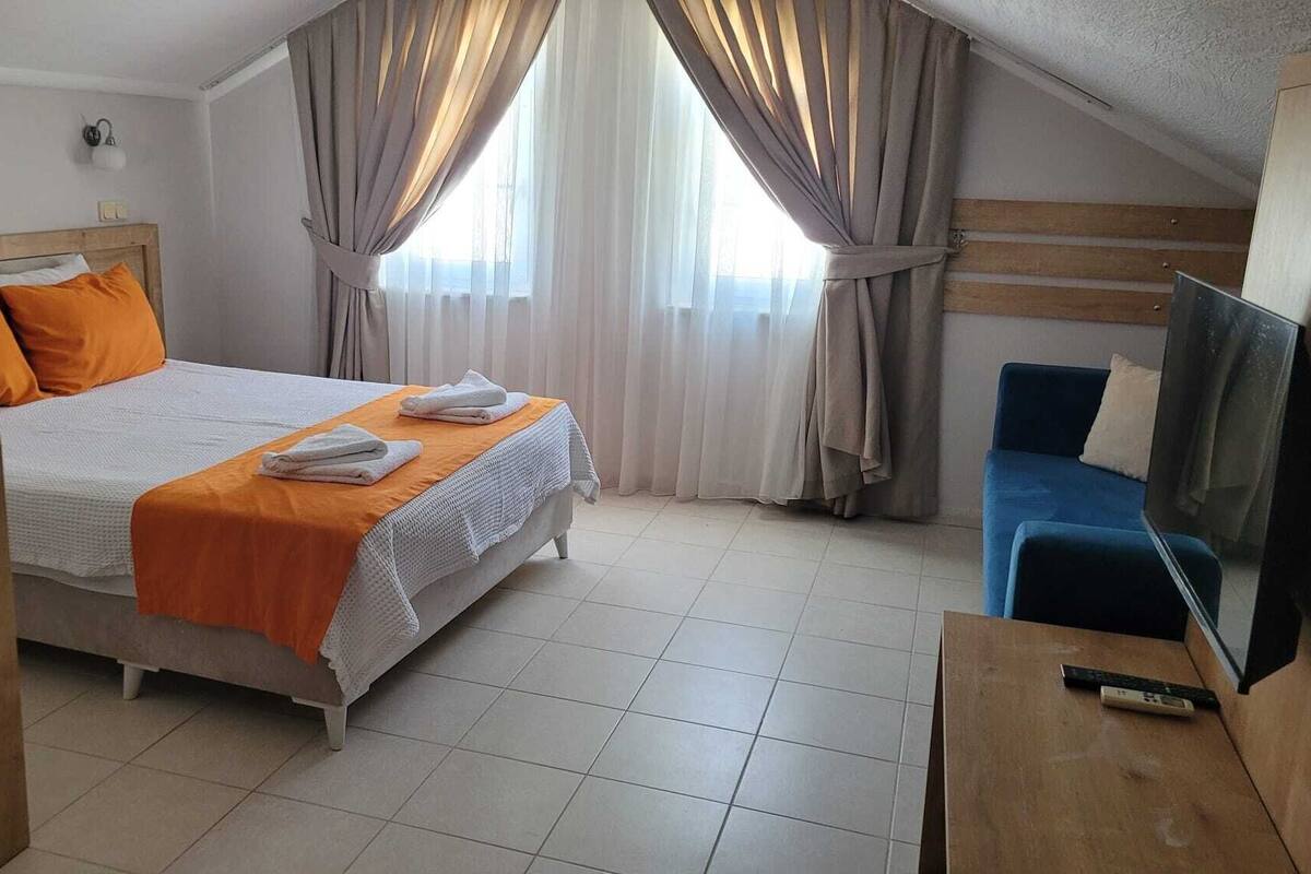 A hotel room with a bed, a TV, and a desk.
