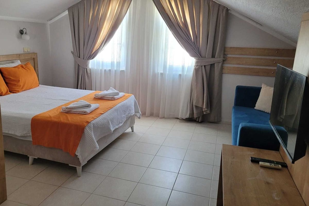 Una habitación de hotel con cama, televisor y escritorio.