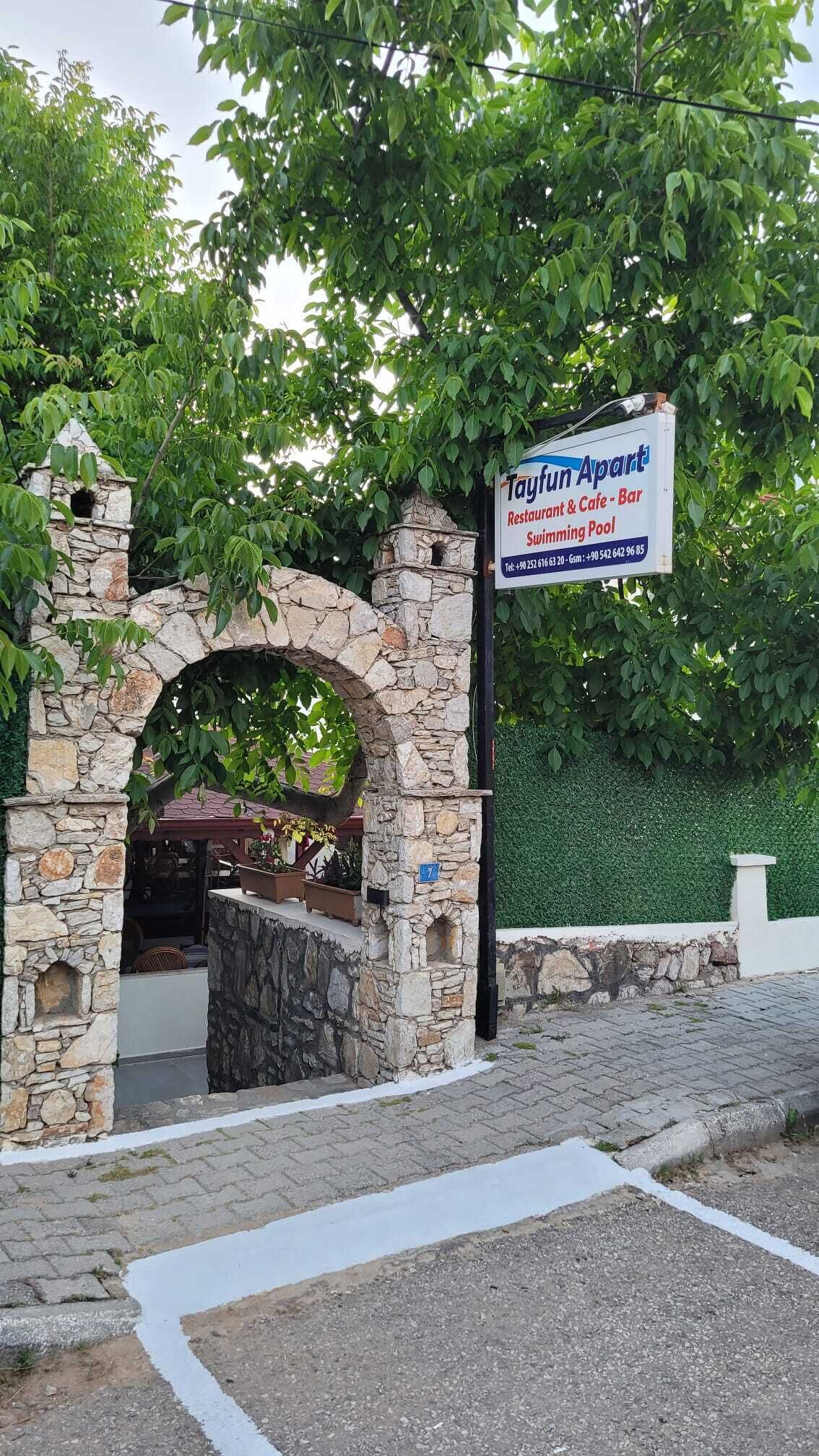 A stone archway leading to a restaurant and bar named 'Tayfun Apart.'