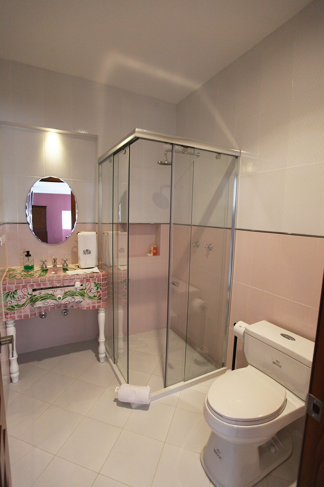 A bathroom with a glass-enclosed shower, a white toilet, and a sink with a decorative tile backsplash.