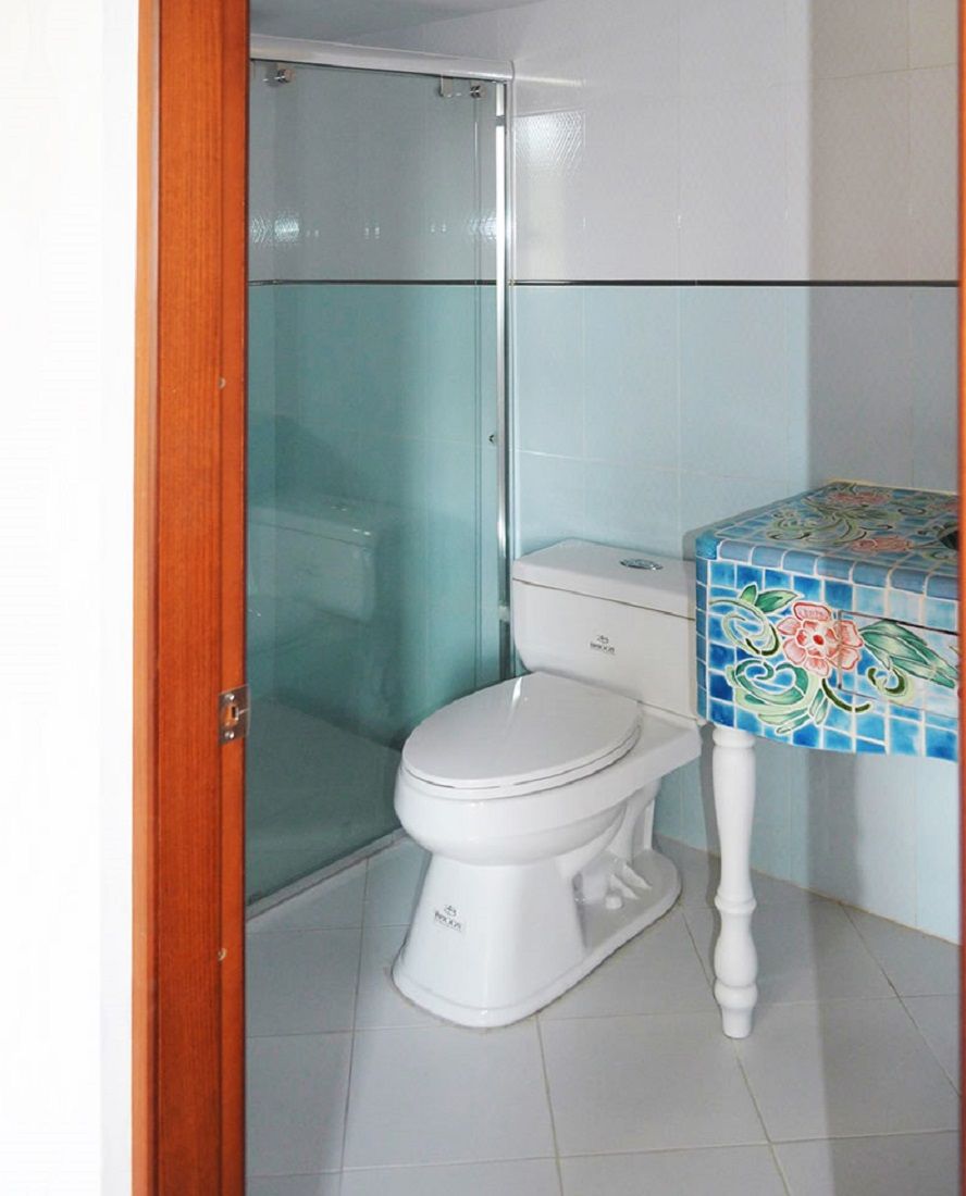 Un baño con inodoro, cabina de ducha y zona de lavamanos con azulejos.