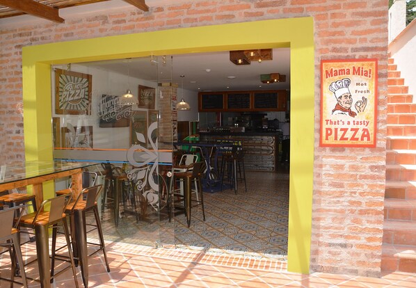 Un restaurante con un mamparo de vidrio, un marco amarillo y un letrero que dice "Mama Mia! Pizza fresca y deliciosa".