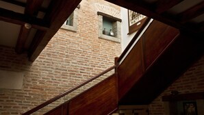 Uma escadaria com corrimãos de madeira e um muro de tijolos ao fundo.
