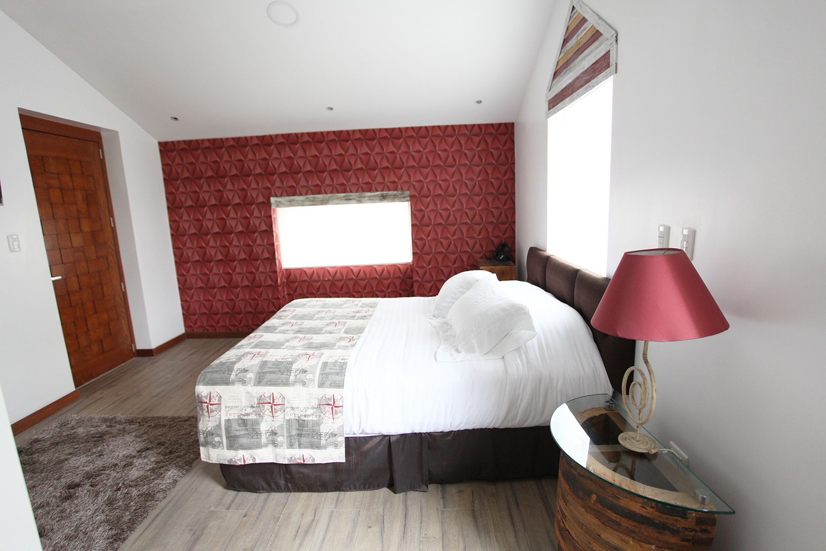 Una camera da letto con un letto, un comodino, una lampada, una finestra e una porta.