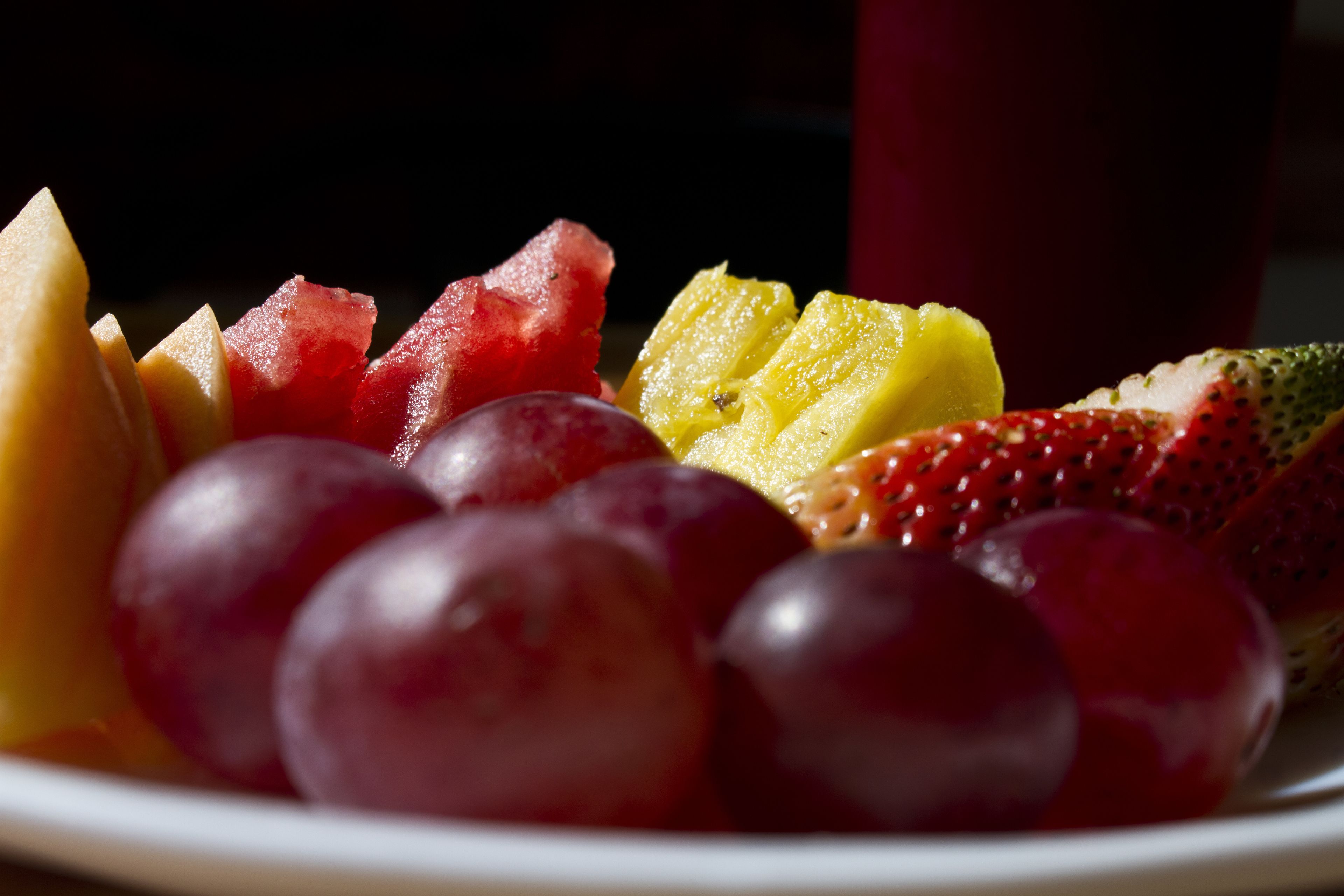 En tallrik med ett urval av olika frukter, inklusive vattenmelon, kiwi, vindruvor och jordgubbar.