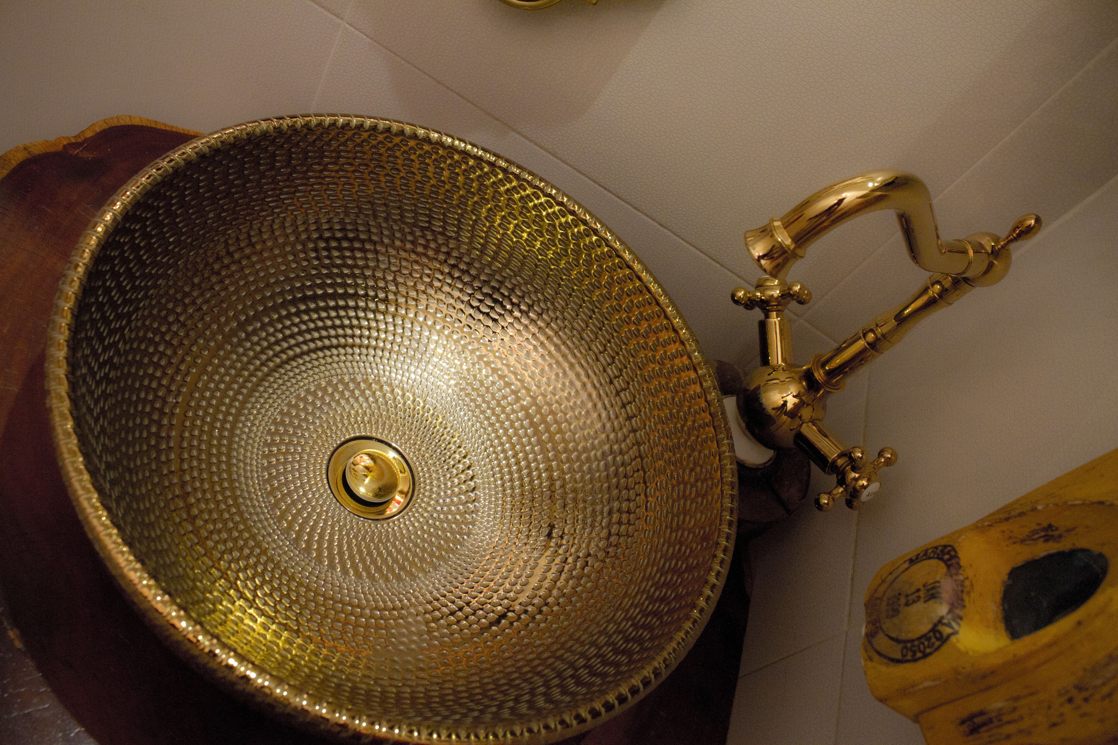 Ein goldfarbenes, strukturiertes Waschbecken mit einem Wasserhahn.