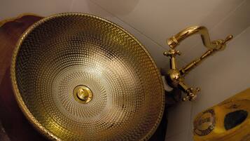 Ein goldfarbenes, strukturiertes Waschbecken mit einem Wasserhahn.