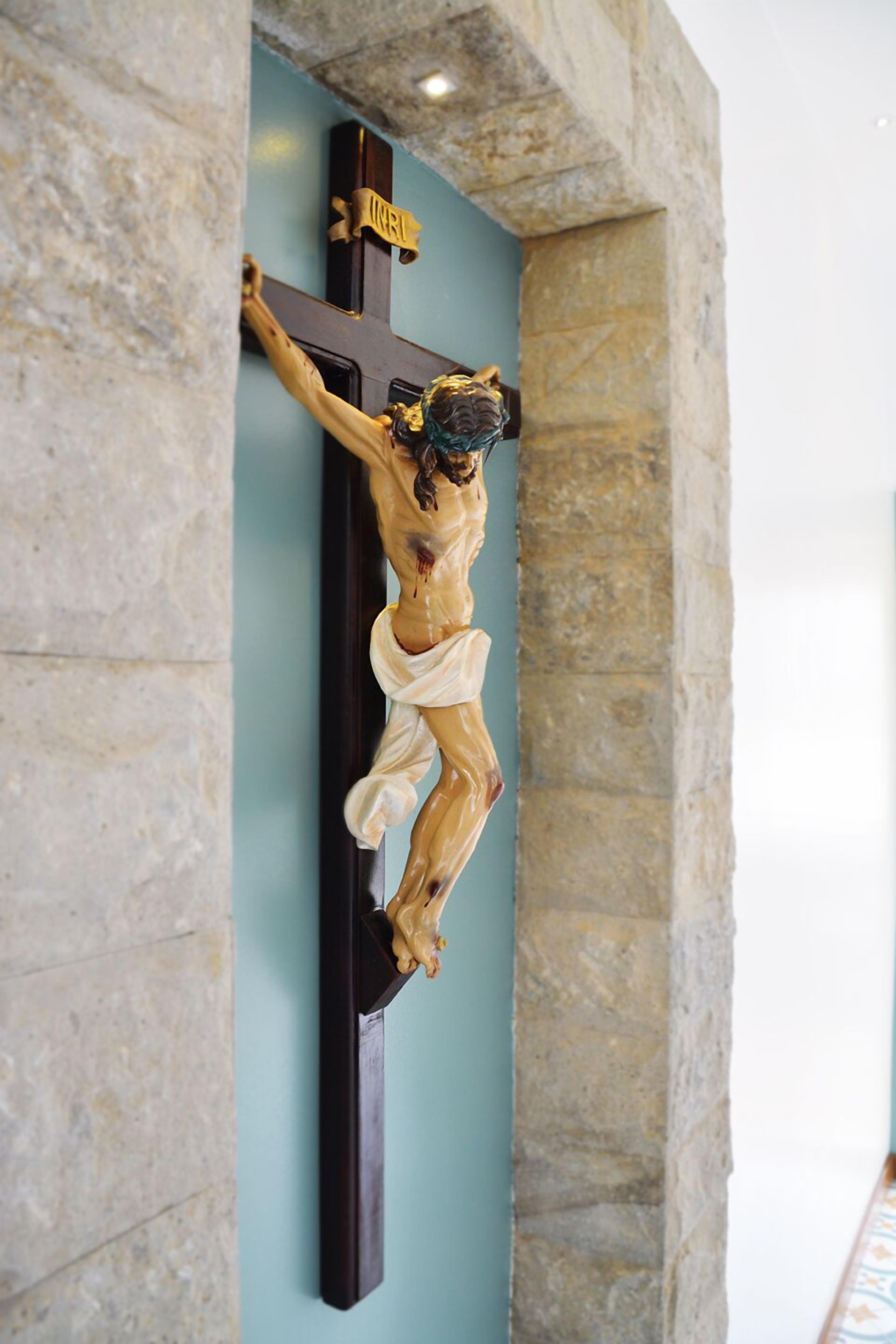 A crucifix mounted on a wall with stone masonry.