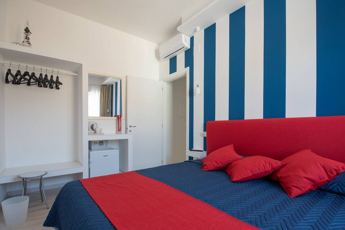 A bedroom with a large bed, a desk, and a wardrobe.