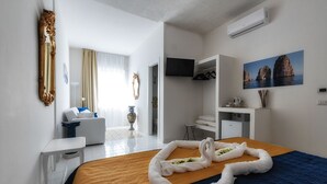 Moderni hotellihuone, jossa on sänky, työpöytä, televisio ja vaatekaappi.