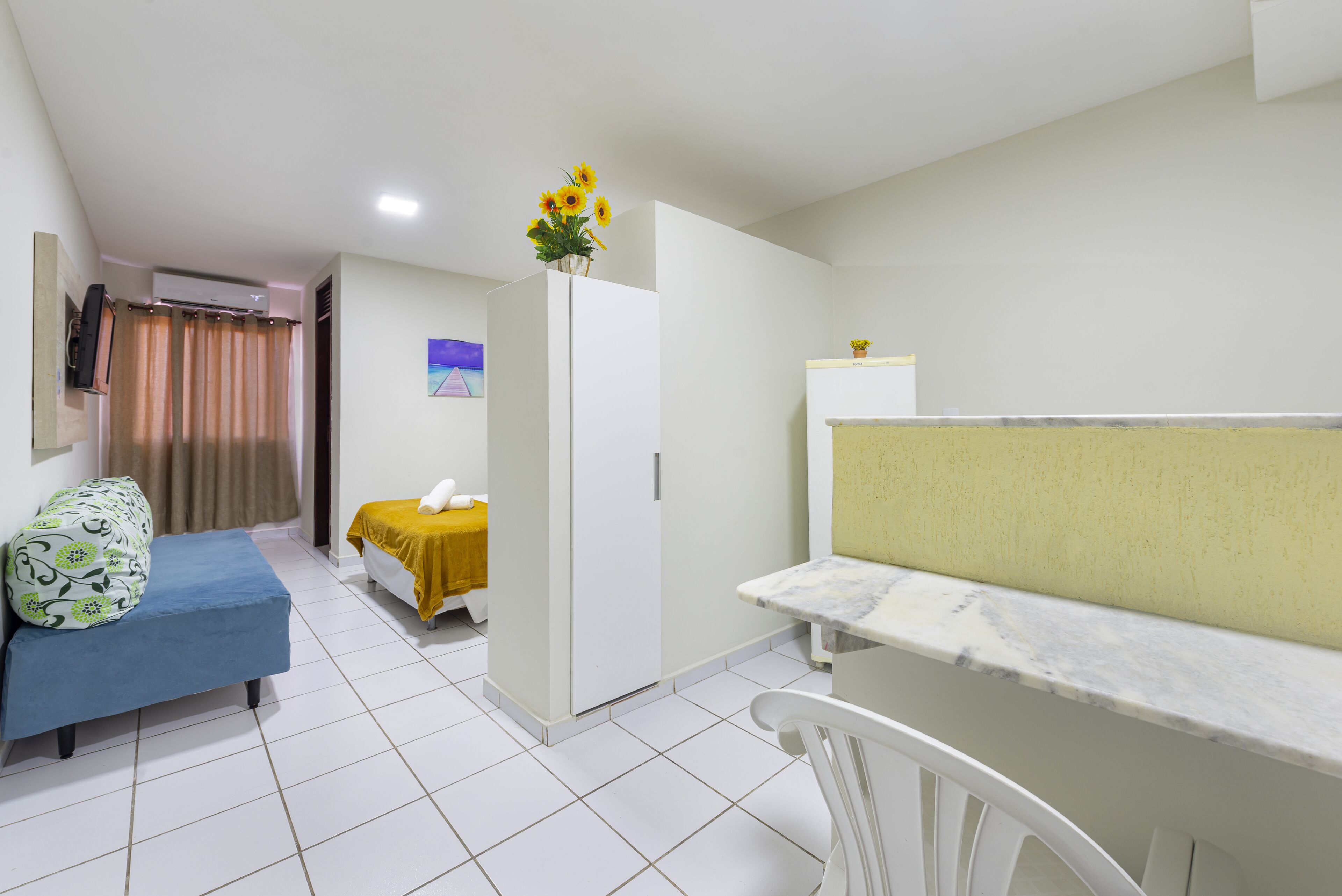 A compact room with a bed, a small table, a sofa, and a cabinet.